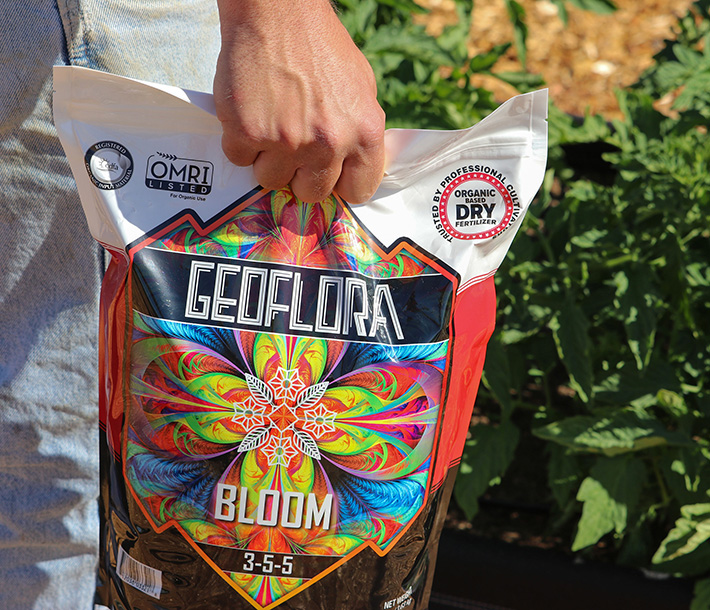 A gardener carries a bag of Geoflora BLOOM to prepare it for application